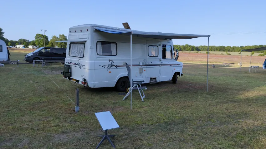 1970's camper on a campsite with a canopy